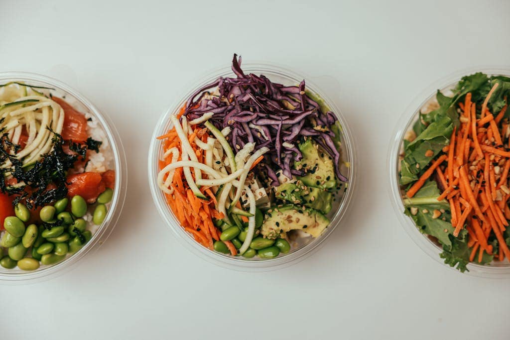 Top view of three healthy salad bowls featuring fresh mixed vegetables, perfect for a nutritious meal.