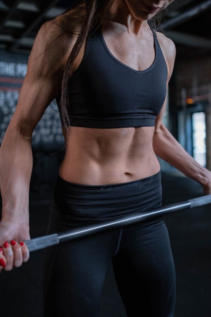 A muscular woman in sportswear lifting a barbell in a gym, promoting fitness and strength.