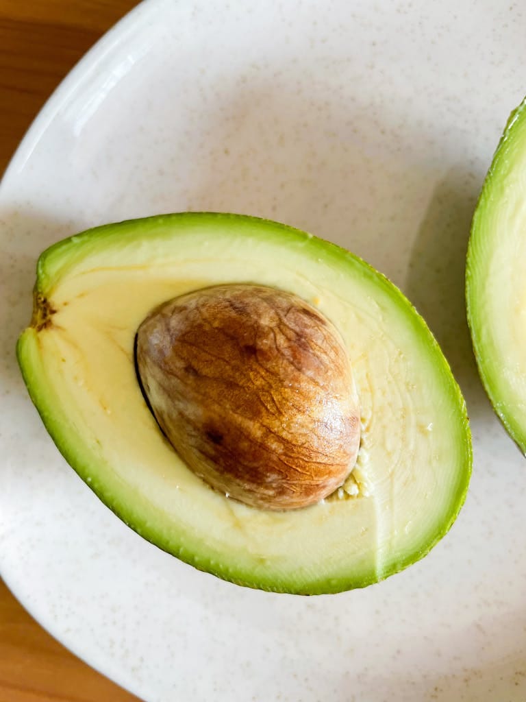 Close-up of fresh avocado halves on a white plate, showcasing healthy nutrition.