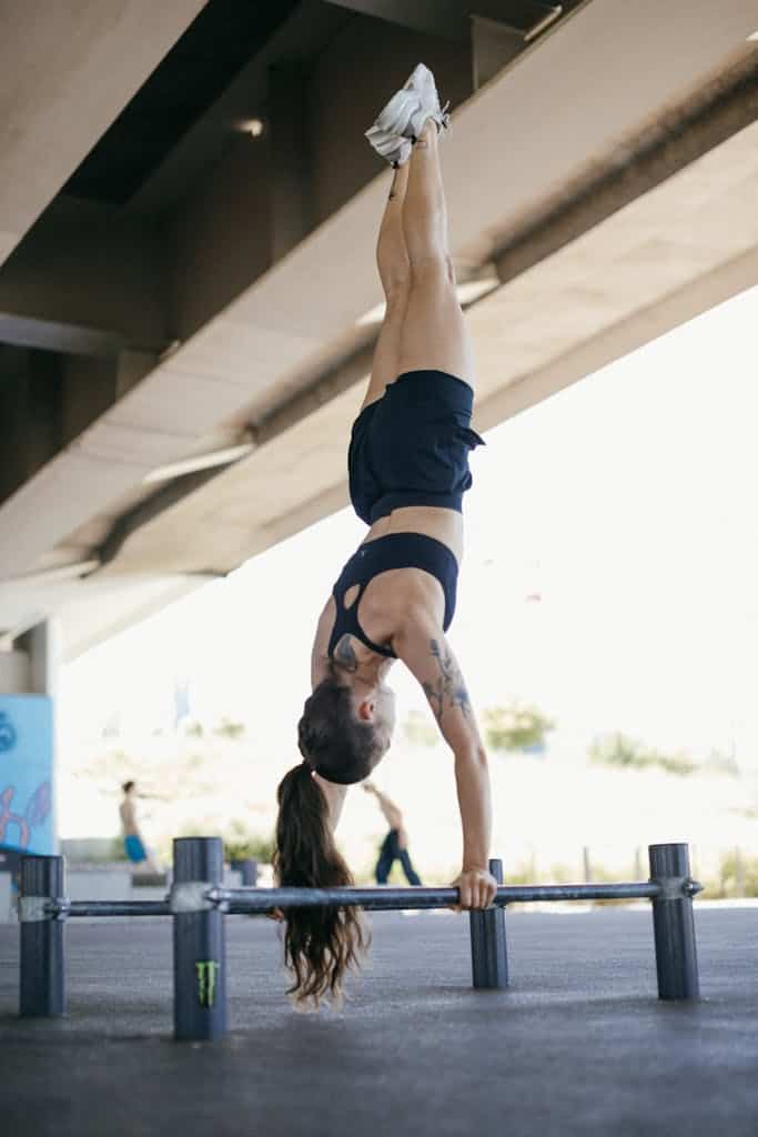 Woman performing a handstand in an outdoor gym, showcasing strength and balance.