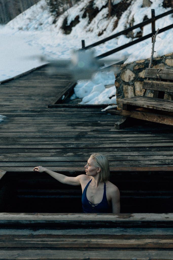 A woman enjoying winter swimming in an icy outdoor pool surrounded by snow.