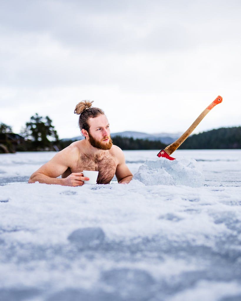 Bearded man with an axe enjoys a cup of coffee during winter swim in Trondheim, Norway.