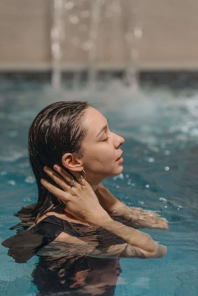 Profile of a woman relaxing in a swimming pool with serene expression and wet hair.