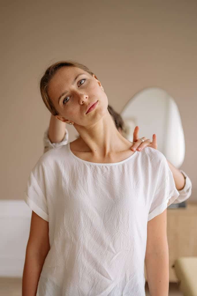 A woman in a white shirt receives a gentle neck stretch from a therapist to help fix neck hump