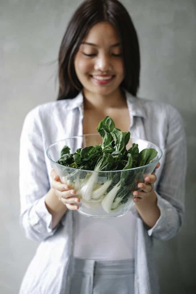 woman holding anti-tinflammatory foods like bok choy to help excess estrogen and fibroids naturally
