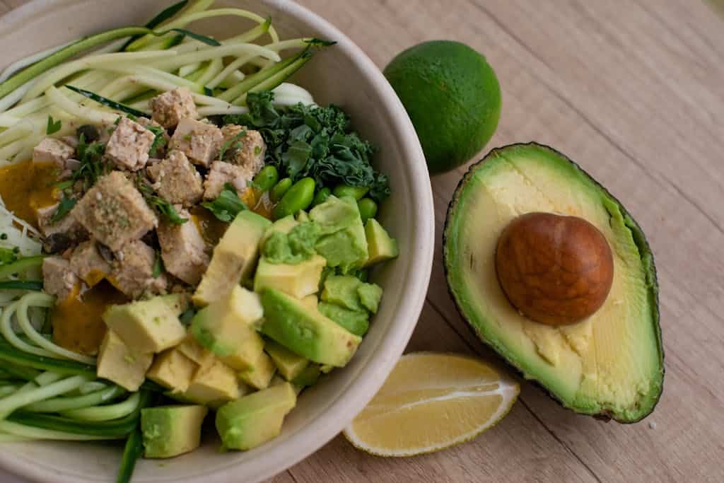 Delicious vegan bowl with zoodles, avocado, tofu, and greens providing healthy fats and cuciferous vegetables